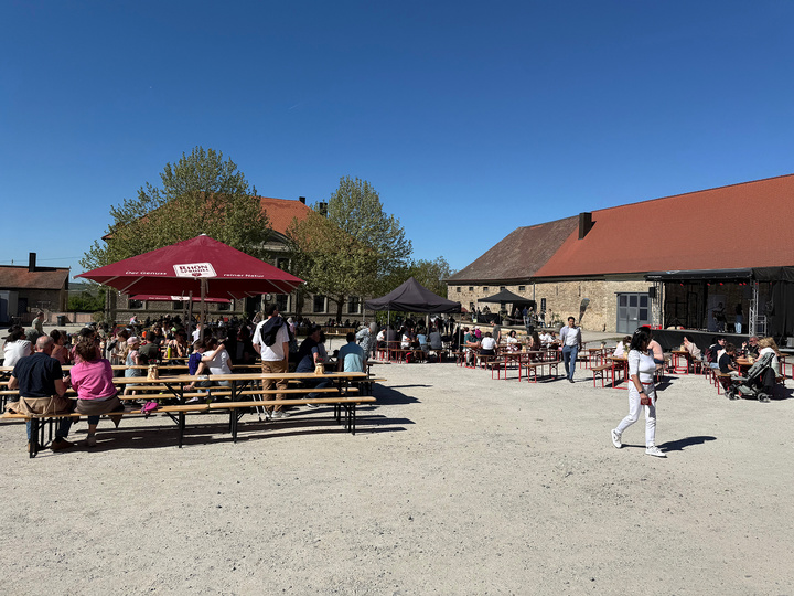 Besucher sitzen an Bänken im Innenhof bei Sonnenschein